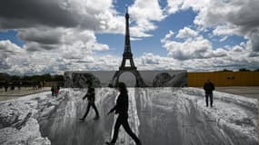 Des personnes marchent sur l'esplanade du Trocadéro, en face de la Tour Eiffel, sur un trompe-l'oeil de l'artiste  français de street-art JR, le 19 mai 2021 à Paris