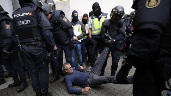 Des policiers emmènent un manifestant de force, devant un bureau de vote, à Barcelone, le 1er octobre. Des policiers emmènent un manifestant de force, devant un bureau de vote, à Barcelone, le 1er octobre.