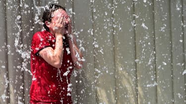 Une jeune fille se rafraîchit dans une fontaine.
