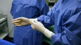 Un chirurgien enfile des gants avant d'opérer un patient, à Paris le 1er novembre 2003