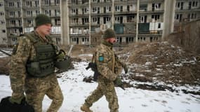 Des soldats ukrainiens marchent devant des immeubles endommagés sur la ligne de front avec l'Est séparatiste, à Marinka près de Donetsk le 7 février 2022