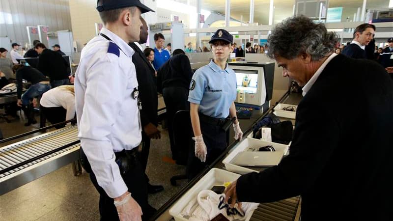 Des policiers épaulent jeudi les agents de sécurité non grévistes de l'aéroport parisien de Roissy-Charles de Gaulle pour faciliter le contrôle des passagers face à la reconduction de la grève pour son septième jour. /Photo prise le 22 décembre 2011/REUTE