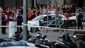 Des passants évacuant les lieux de l'attaque de Barcelone sous l'oeil de la police, le 17 août 2017.