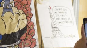 Une personne prend en photo des dessins en hommage au 13-Novembre, exposés aux Archives de Paris
