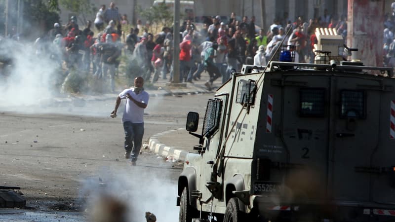 Des manifestant palestiniens face à un véhicule de l'armée israélienne, près de la prison d'Ofer le 15 mai 2014.