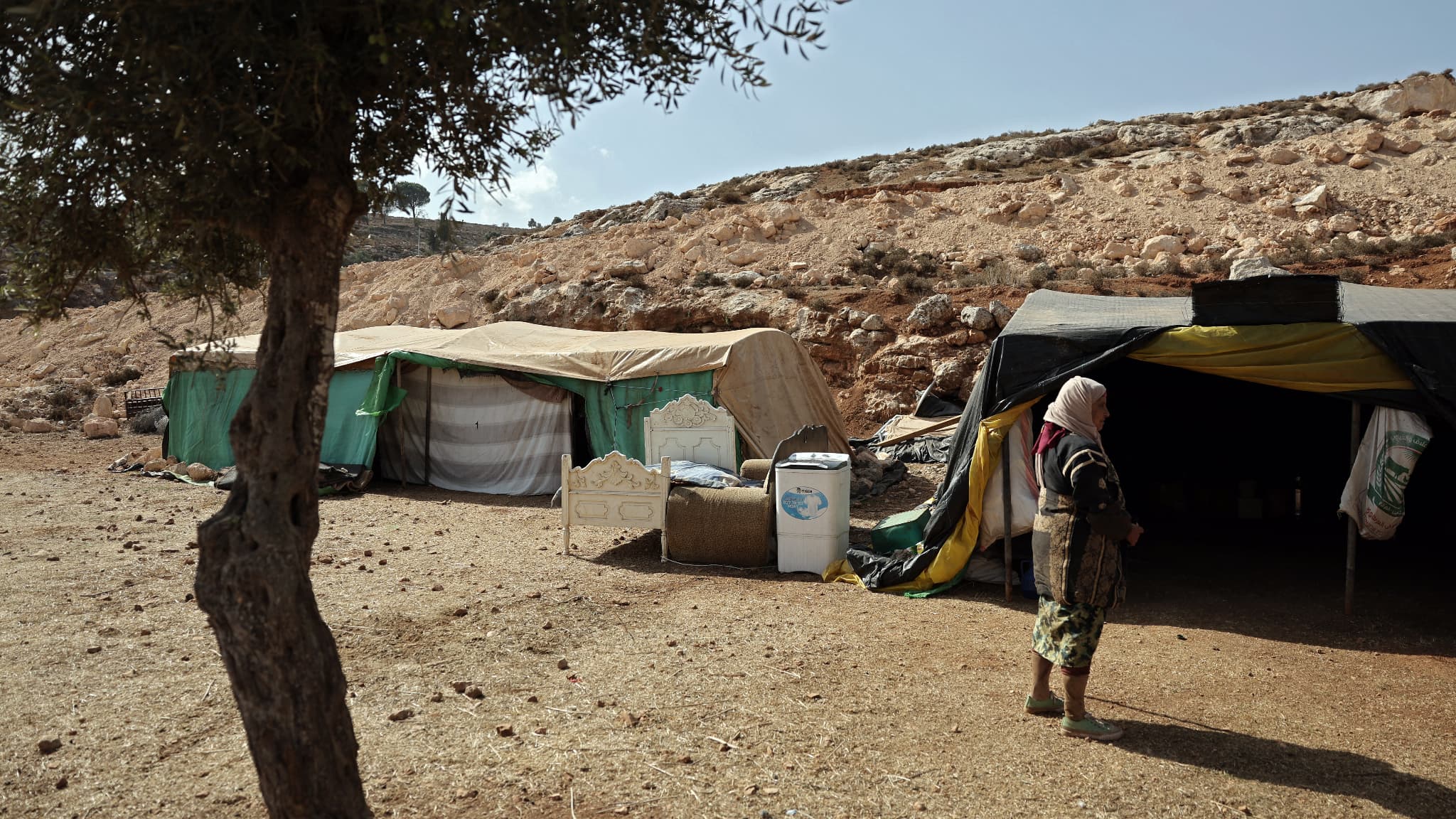 Une femme dans des abris temporaires installés dans la ville de Taybeh, en Cisjordanie, où sa communauté a trouvé refuge après l'attaque de son village par des colons israéliens, le 24 octobre 2023. 