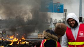 Des syndicalistes participent à une "action de blocage de route", devant un feu, au Havre ce 21 mars 2023.