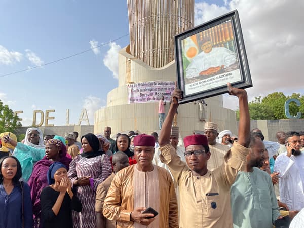 Des partisans du président nigérien Mohamed Bazoum, portant un portrait du président, se rassemblent pour lui manifester leur soutien, à Niamey le 26 juillet 2023.