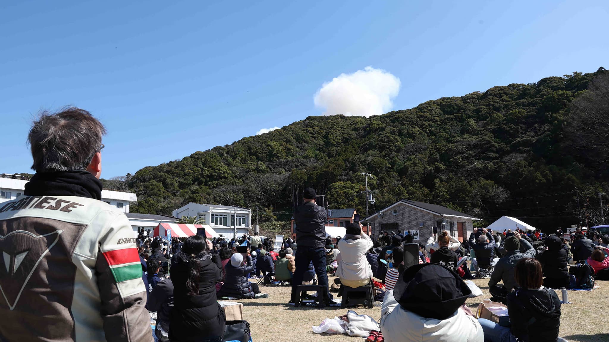 Des visiteurs regardent la fumée s'élever derrière une colline après l'explosion au décollage d'une petite fusée de la société Space One, basée à Tokyo, sur le site du Spaceport Kii à Kushimoto, dans la préfecture de Wakayama, le 13 mars 2024.