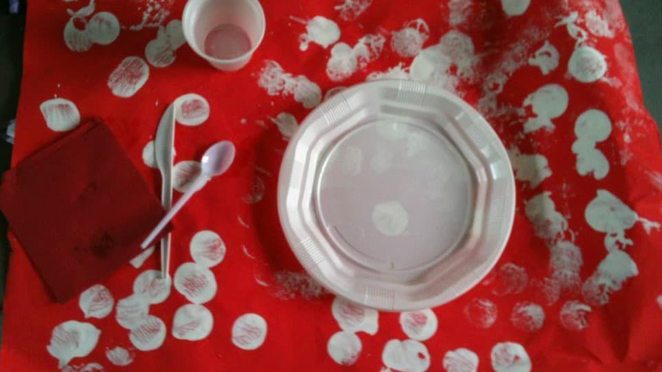 Une feuille A3 peinte en rouge, sur laquelle sont collés des couverts en plastique: un cadeau de Fête des mères pour le moins original.