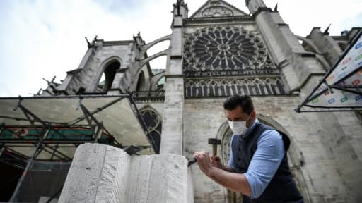 Un tailleur de pierre explique ses gestes à des visiteurs devant la basilique Saint-Denis, le 5 juin 2020