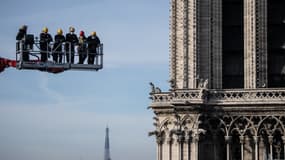 Des ouvriers sur une grue regardent le site de la cathédrale Notre-Dame le 24 novembre 2020 à Paris. 