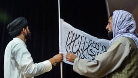 Des talibans accrochent le drapeau du mouvement, mardi 17 août, à Kaboul, lors de la première conférence de presse depuis la prise de la capitale.