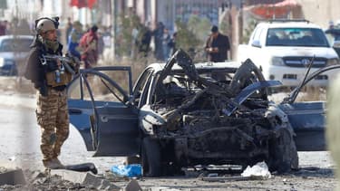Un policier près d'une voiture détruite par une attaque suicide, à Kaboul, le 13 novembre 2019.