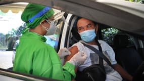 Un receveur du vaccin contre le Covid-19 se fait vacciner au volant à Nusa Dua, l'île balnéaire indonésienne de Bali, le 1er mars 2021.