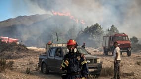 Un pompier observe les feux de forêt qui brûlent les forêts des collines près du village de Vati, dans la partie sud de l'île grecque de Rhodes, le 25 juillet 2023.
