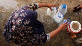 Une femme remplit des bouteilles avec de l'eau potable, dans un hôpital de campagne, à Nowshera, dans le nord-ouest du Pakistan. Les inondations provoquées dans le pays par des pluies de mousson diluviennes ont fait plus de 1.600 morts, 2 millions de sans
