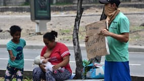 Une famille en train de faire la manche à Tegucigalpa au Honduras en mai 2020, avec un panneau "nous avons faim".