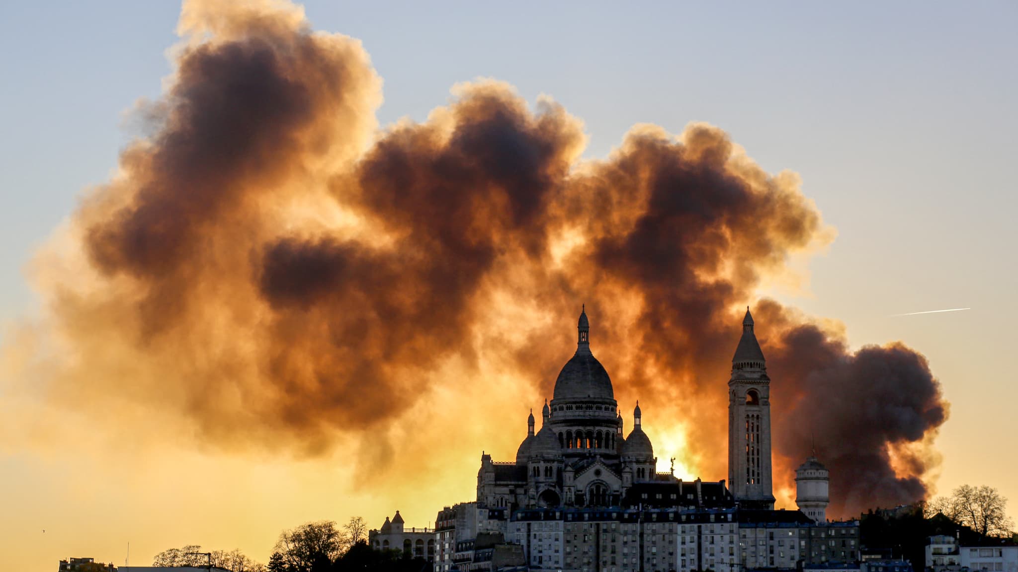De la fumée s'élève derrière la basilique du Sacré-Cœur alors qu'un « incendie majeur » s'est déclaré dans le 17e arrondissement voisin, au nord de Paris, ont annoncé les pompiers, sans préciser les bâtiments touchés, le 7 avril 2025.
