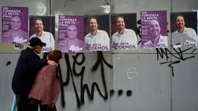 Un couple de madrilènes jeudi devant une affiche de campagne du fondateur du parti anti-austérité Podemos, Pablo Iglesias. 