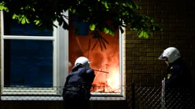 Des policier éteignent un début d'incendie dans une école de Tensta, dans la banlieue de Stockholm, où ont lieu pour la sixième nuit consécutive des émeutes.