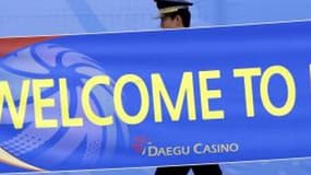 Un officier de police coréen passe devant une banderole de bienvenue au village des athlètes à Daegu