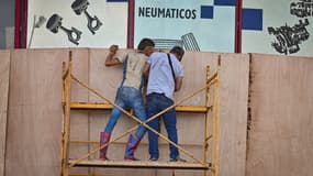 Des travailleurs cubains protègent la devanture d'un commerce avant l’arrivée de l'ouragan Rafael à La Havane. Le 5 novembre 2024.