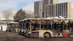 Cette photographie, prise lors d'une visite organisée pour des médias étrangers, montre un représentant de la presse passant devant des bus incendiés dans un dépôt lors des récentes manifestations à Téhéran, le 21 janvier 2026.