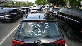 Un slogan "Taxis en colère" est inscrit sur une voiture alors que des chauffeurs de taxi participent à une opération de blocage à Pau, 
le 19 mai 2025