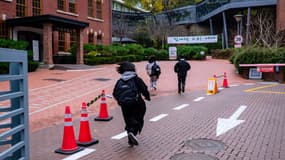 Des étudiants courent alors qu'ils arrivent pour passer l'examen annuel d'entrée à l'université au  lycée Ehwa à Séoul, le 16 novembre 2023. 