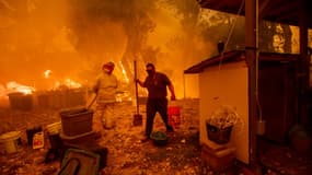 Lane Lawder, habitante de New Long Valley Road près de Clearlake Oaksde, porte un sceau d'eau, alors qu'elle tente de sauver sa maison des flammes du Ranch Fire en Californie le 6 août 2018.
