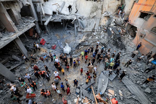 Des membres de la défense civile palestinienne et des habitants se rassemblent sur le site d'un bâtiment touché par un bombardement israélien à Khan Yunis, dans le sud de la bande de Gaza, le 19 octobre 2023.