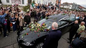 Des fans lancent des fleurs sur le corbillard de Sinéad O'Connor tandis qu'il passe devant l'ancienne maison de la chanteuse, le 8 août 2023 dans la ville irlandaise de Bray