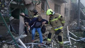 Cette photo prise et diffusée par le Service d'urgence de l'État ukrainien le 23 juin 2025 montre des sauveteurs évacuant des habitants d'un bâtiment endommagé à la suite de frappes nocturnes de drones et de missiles russes à Kiev