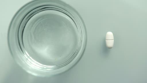 Un médicament et un verre d'eau, image d'illustration