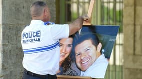 Un policier municipal retire la photo du couple de policiers de Magnanville, dans les Yvelines tué à son domicile, après une cérémonie leur rendant hommage à Pézenas, dans l'Hérault, le 20 juin 2016