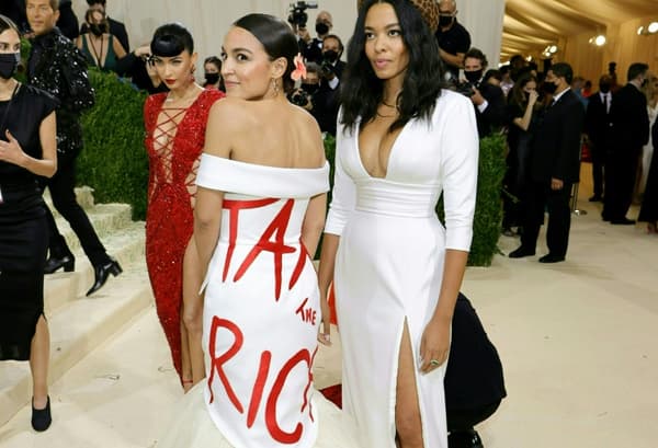 Alexandria Ocasio-Cortez (g) en robe de soirée blanche marquée du message en lettres rouges "Tax the Rich" ("Taxez les riches) au gala du Metropolitan Museum of Art (Met), le 13 septembre 2021 à New York 
