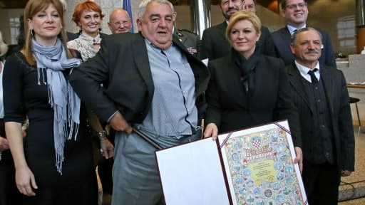 Le patron du Comité Helsinki croate pour les droits de l'homme, Ivan Zvonimir Cicak (C), remonte son pantalon, à côté de la présidente croate Kolinda Grabar Kitarovic (2ed), à Zagreb, le 8 décembre 2015