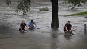 Des gens traversent un parc inondé à Penrith, dans la banlieue ouest de Sydney, le 21 mars 2021