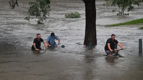 Des gens traversent un parc inondé à Penrith, dans la banlieue ouest de Sydney, le 21 mars 2021
