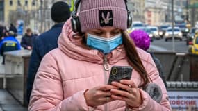 Une femme masquée consultant son iPhone, à Moscou, en mars 2021