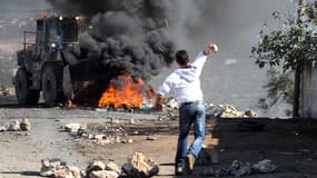 Un jeune Palestinien jette une pierre sur un bulldozer israélien pour protester contre la construction de nouvelles colonies.