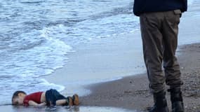 Un officier de police turc devant le corps d'Aylan Kurdi, petit réfugié syrien retrouvé mort sur une plage de Bodrum, au sud de la Turquie, le 2 septembre 2015, après le naufrage d'une embarcation.