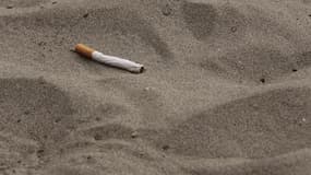 Un mégot de cigarette dans le sable.