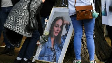 Une femme dépose une rose sous un portrait de Justine Vayrac, la jeune femme de 20 ans tuée après une sortie d'une discothèque, le 6 novembre 2022 lors d'une marche blanche à Saint-Céré (Lot) 