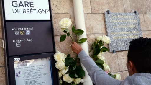 Un homme dépose une rose blanche à la gare de Bretigny-sur-Orge, photo du 12 juillet 2014