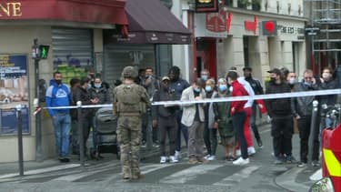 Un soldat et des passants sur les lieux de l'attaque à l'arme blanche le 25 septembre 2020 dans le XIe arrondissement de Paris
