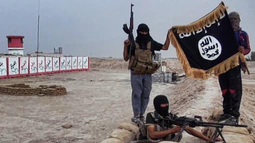 Des combattants de L'EEIL posant avec un drapeau jihadiste à un checkpoint.