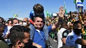 Le président brésilien Jair Bolsonaro porte le fils d'un de ses partisans lors d'un rassemblement à Brasilia le 31 mai 2020