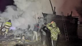 Des hommes et un pompier sur le site d'un incendie dans une maison de retraite du village d'Ishbuldino dans la région du Bachkortostan en Russie centrale, le 15 décembre 2020.